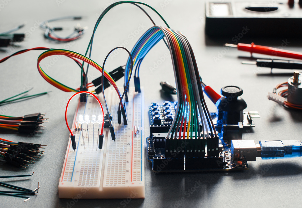 Electronic component connected with breadboard in laboratory. Electrical engineering with led and microcontroller on programmer workplace. Hacker conduct experiment with computer technologies