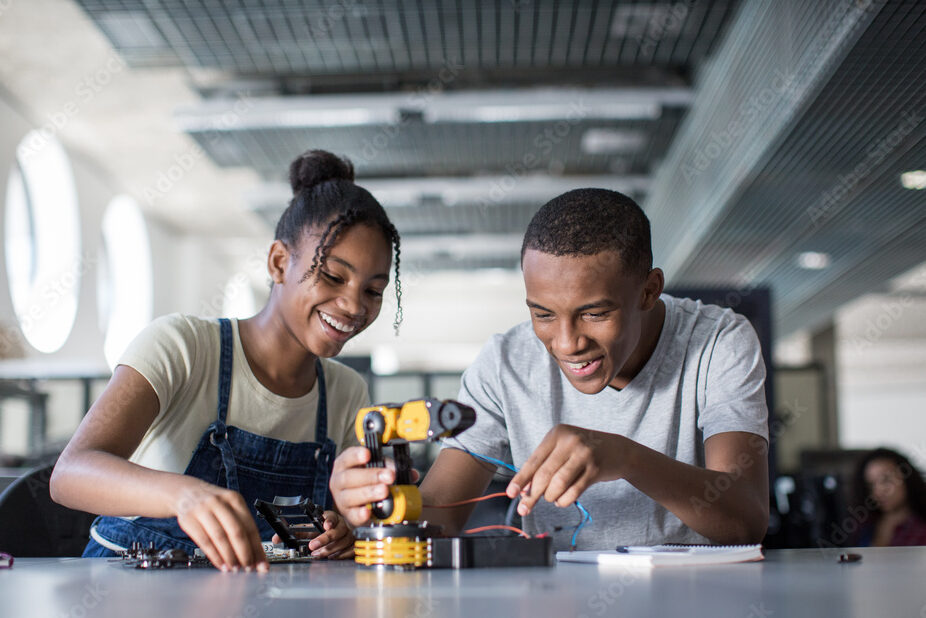 High school students working on a robotic arm in class