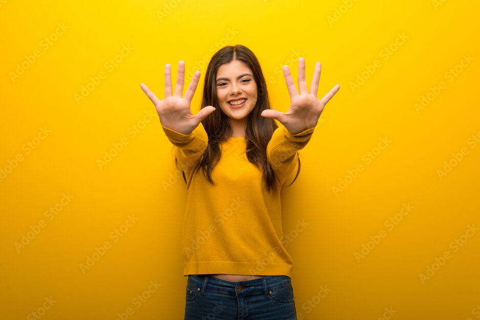 Teenager girl on vibrant yellow background counting ten with fingers